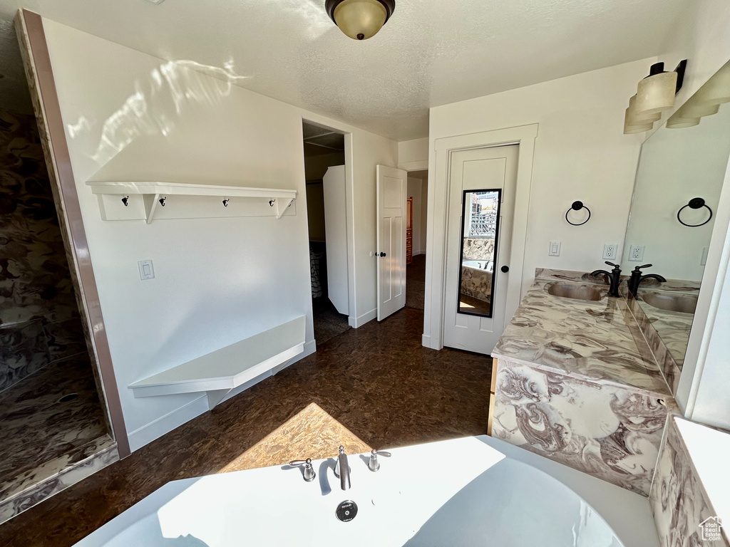 Bathroom featuring a bathing tub, a textured ceiling, vanity, and baseboards