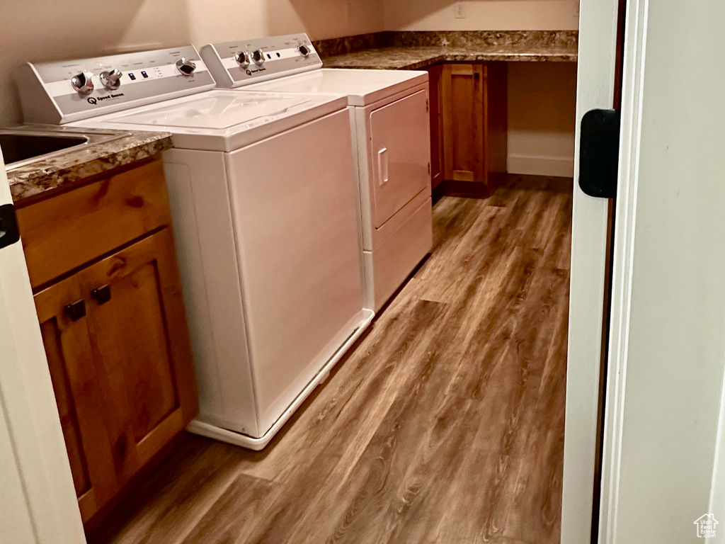 Washroom with cabinet space, a textured ceiling, independent washer and dryer, and wood finished floors