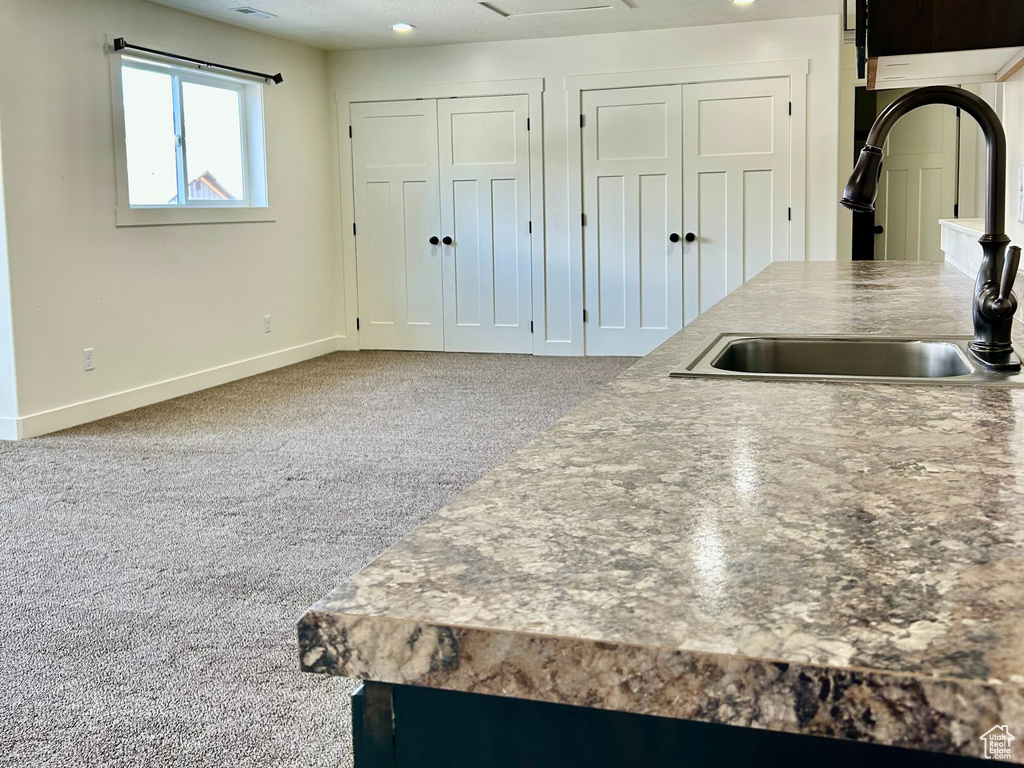 Kitchen with a sink, a textured ceiling, recessed lighting, carpet floors, and baseboards