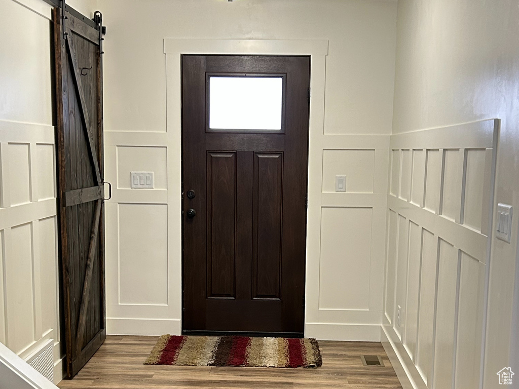Foyer with a barn door, a decorative wall, wood finished floors, and a textured ceiling