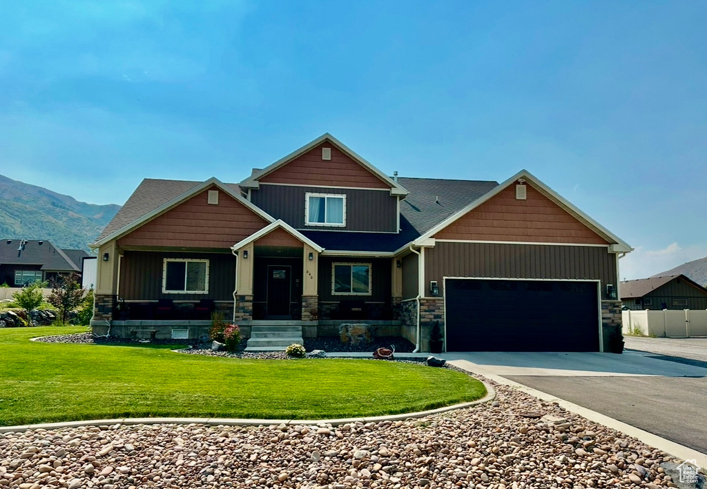 Craftsman-style home featuring a porch, concrete driveway, a front yard, a garage, and stone siding