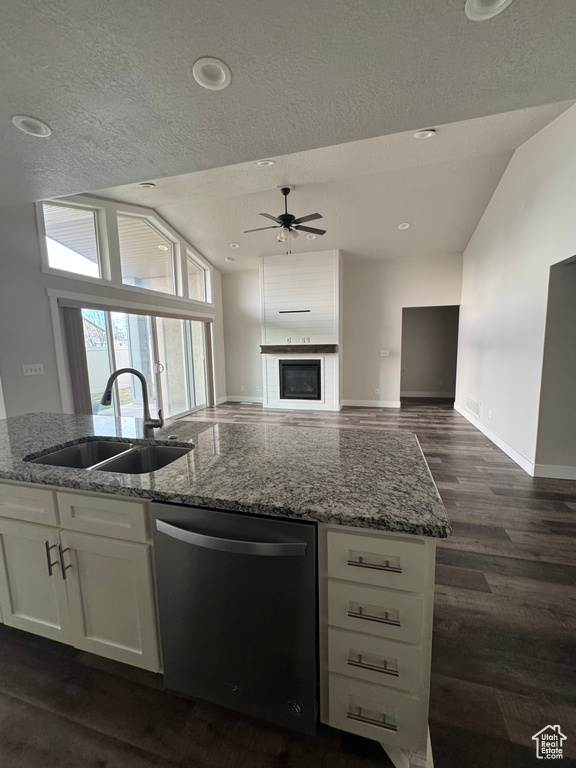 Kitchen featuring stainless steel dishwasher, light stone counters, open floor plan, and a sink
