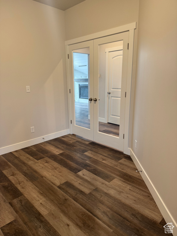 Unfurnished room with dark wood-style floors, baseboards, and french doors