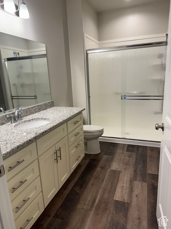 Full bath with wood finished floors, toilet, a stall shower, and vanity