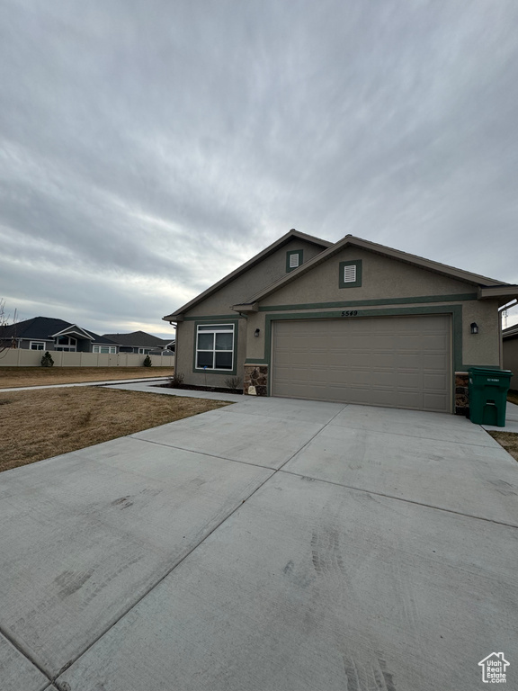 Ranch-style home featuring stone siding, stucco siding, driveway, and a garage