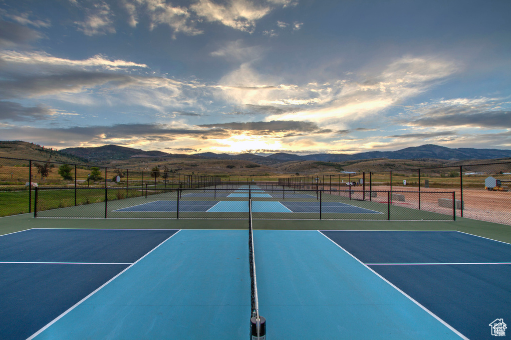 View of tennis court featuring a mountain view, community basketball court, and fence
