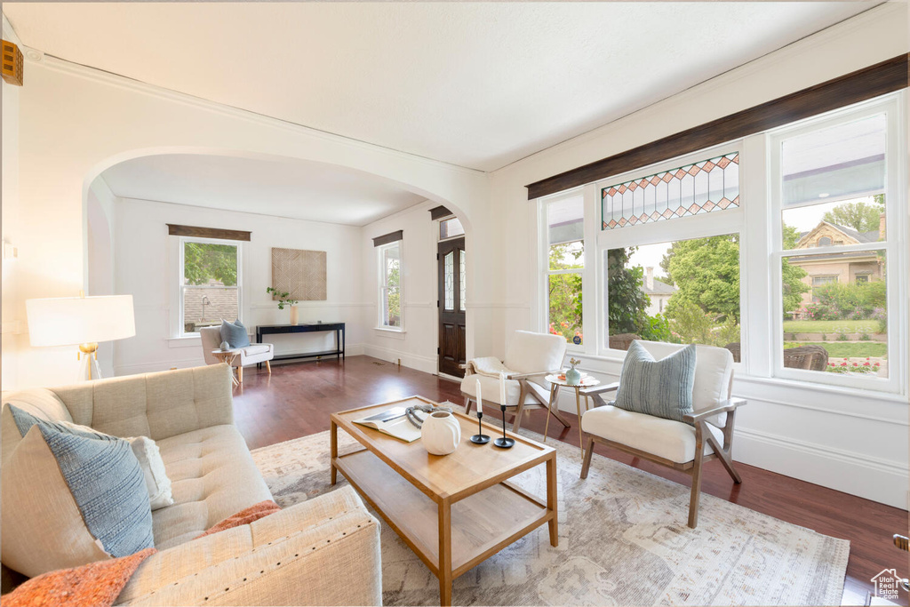 Living area featuring arched walkways, baseboards, and wood finished floors