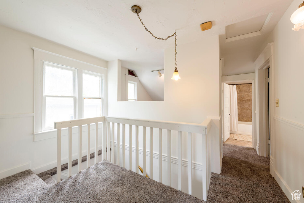Corridor with carpet flooring, an upstairs landing, and vaulted ceiling