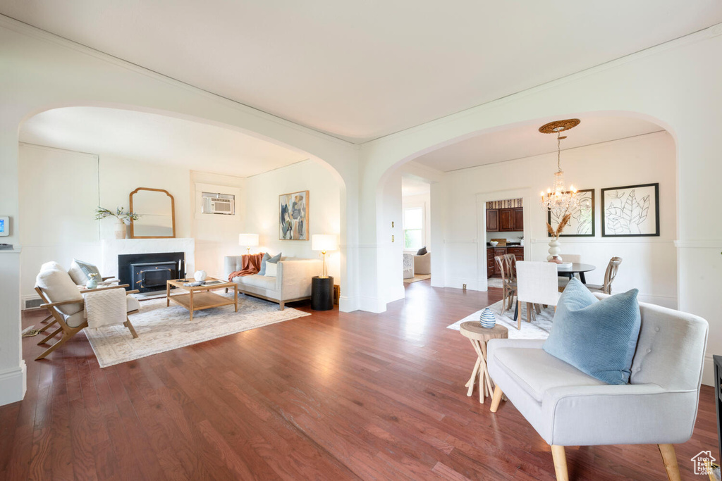 Living room featuring arched walkways, wood finished floors, a chandelier, and a glass covered fireplace