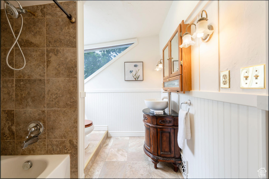 Bathroom featuring wainscoting, bathing tub / shower combination, toilet, and vanity