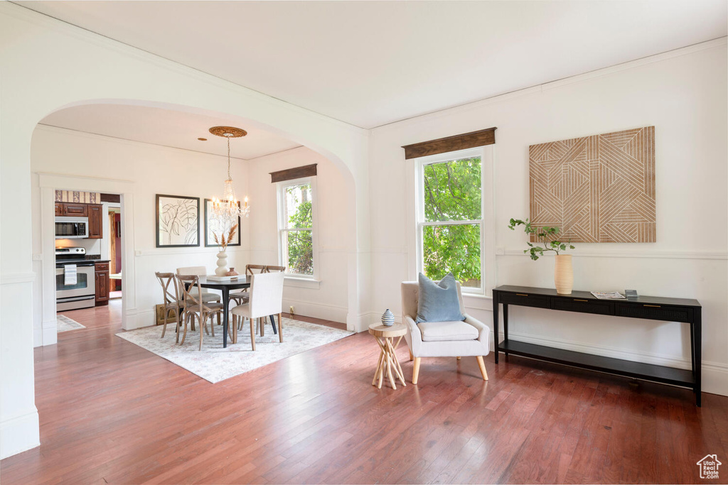 Dining area with arched walkways, wood finished floors, a chandelier, and baseboards