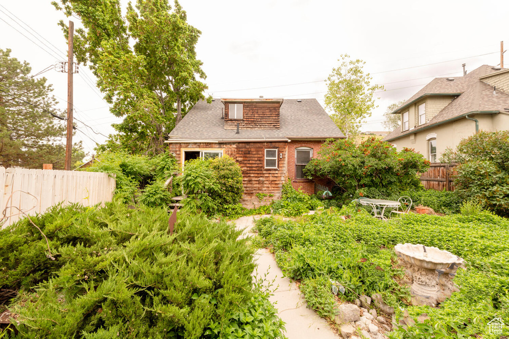 Back of property featuring fence and roof with shingles