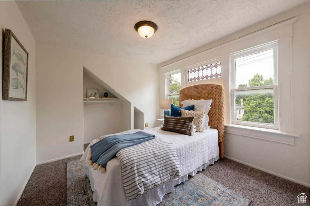 Carpeted bedroom featuring a textured ceiling and baseboards