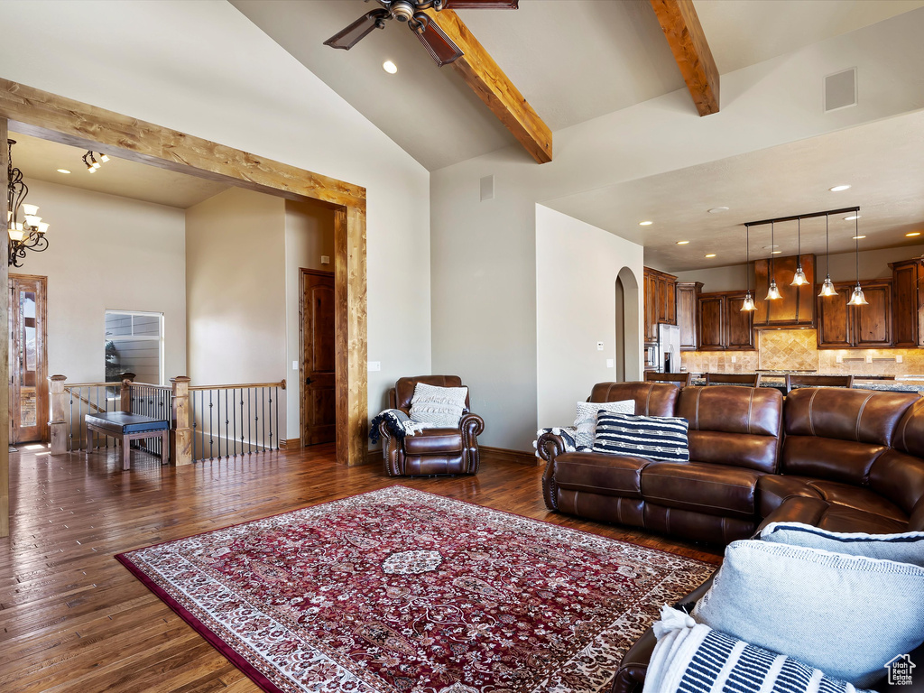 Living room with arched walkways, beamed ceiling, high vaulted ceiling, and dark wood-style flooring