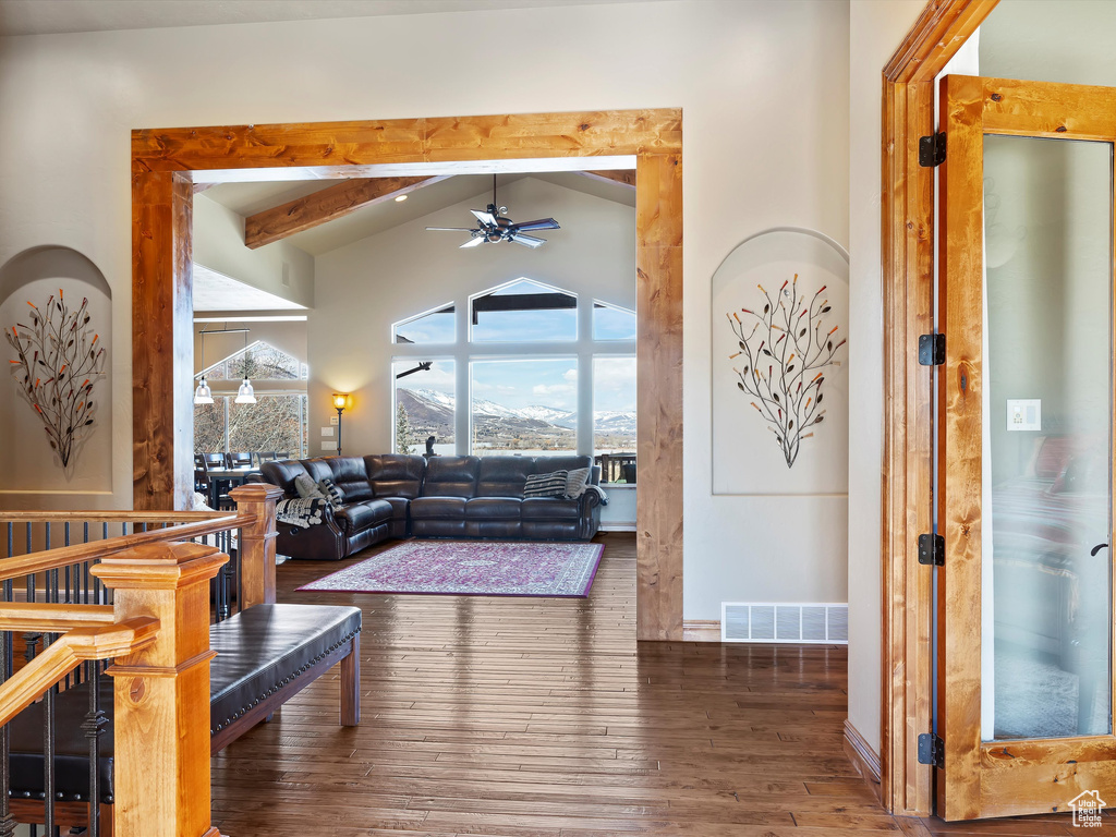 Living room with visible vents, vaulted ceiling with beams, baseboards, hardwood / wood-style floors, and a ceiling fan