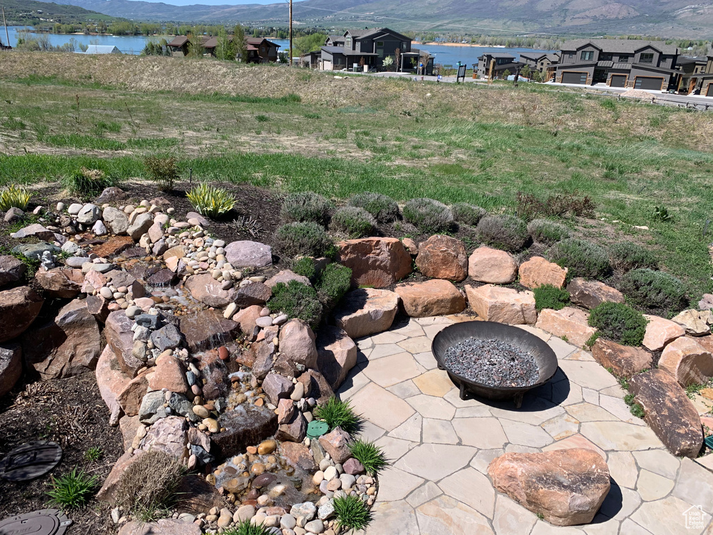 Exterior space with a water and mountain view, a fire pit, and a patio