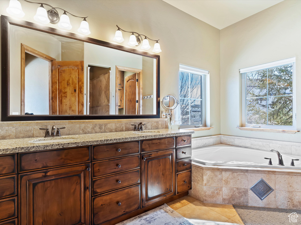 Bathroom featuring double vanity, a bath, tile patterned floors, and a sink