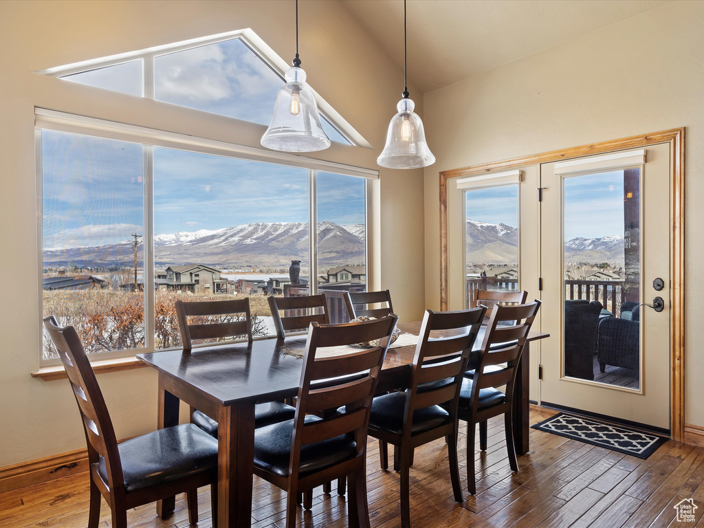 Dining area with hardwood / wood-style flooring, baseboards, a mountain view, and vaulted ceiling
