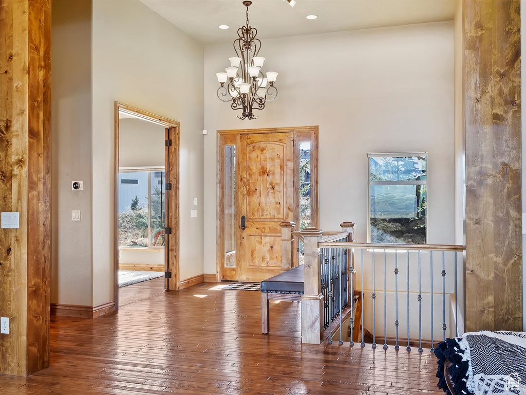 Foyer featuring a wealth of natural light, a high ceiling, an inviting chandelier, and hardwood / wood-style floors