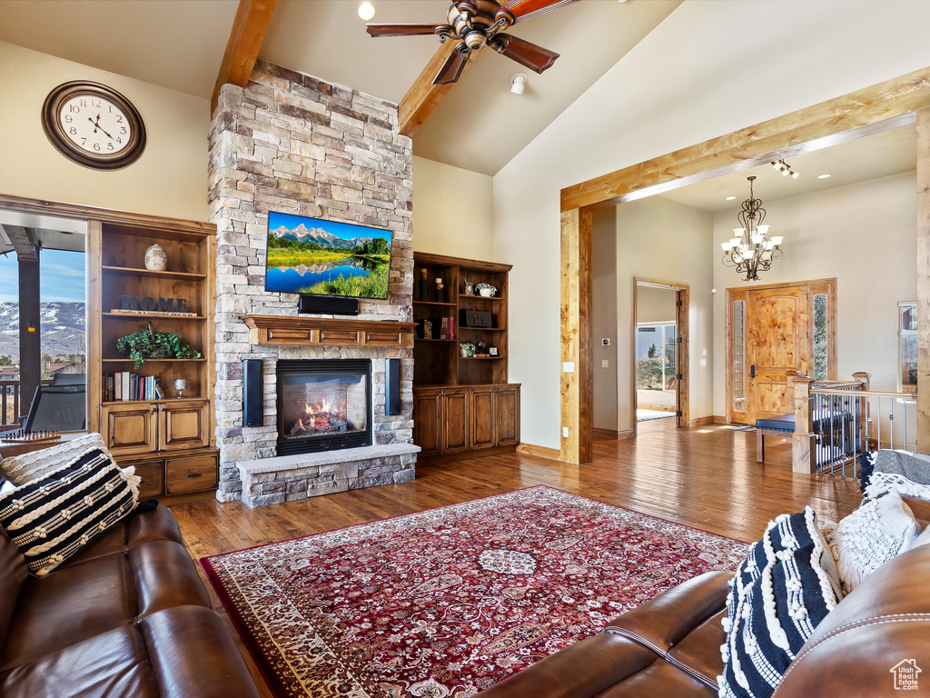 Living area with beam ceiling, high vaulted ceiling, wood finished floors, and a fireplace