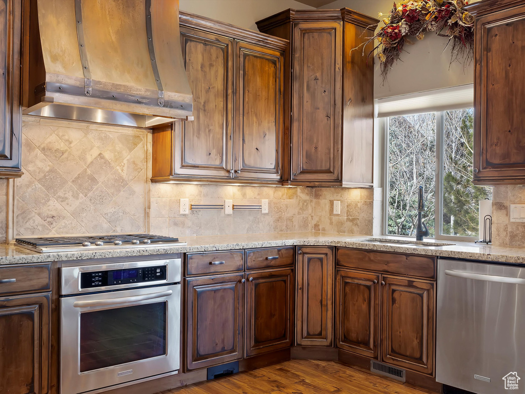 Kitchen featuring visible vents, a sink, extractor fan, appliances with stainless steel finishes, and backsplash