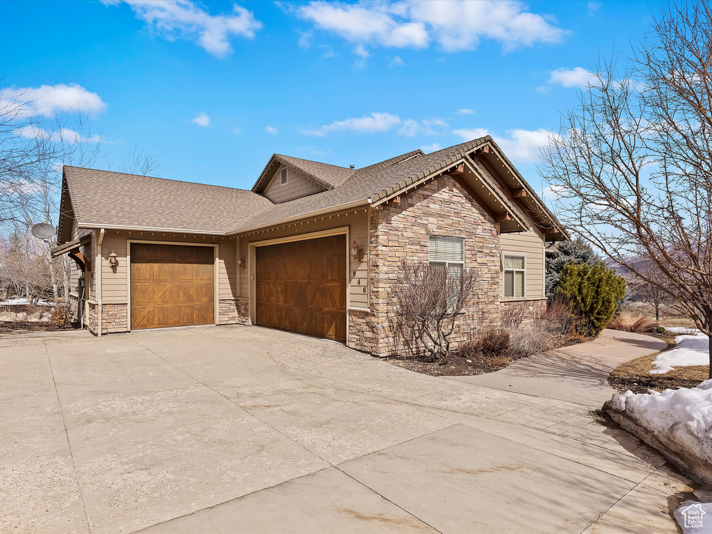 View of side of property with a garage, stone siding, and driveway