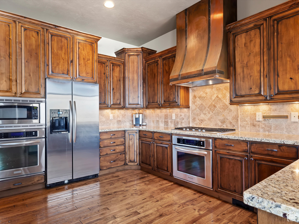 Kitchen with custom range hood, tasteful backsplash, and stainless steel appliances