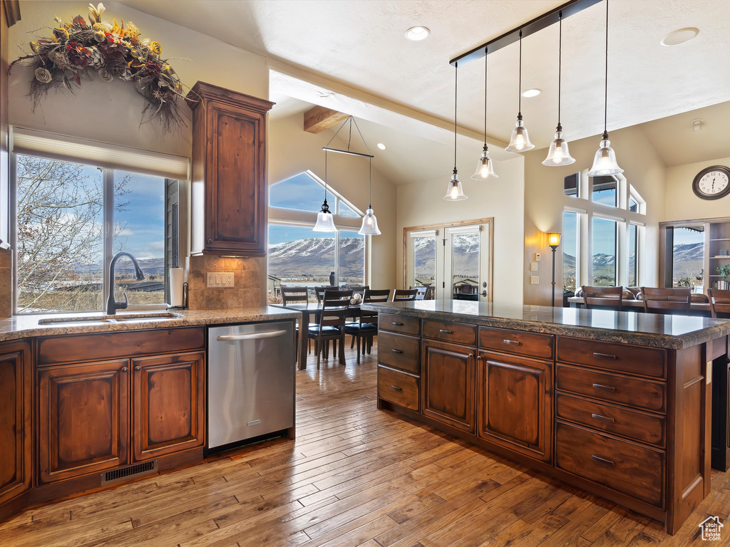 Kitchen featuring light wood finished floors, visible vents, lofted ceiling with beams, stainless steel dishwasher, and a sink
