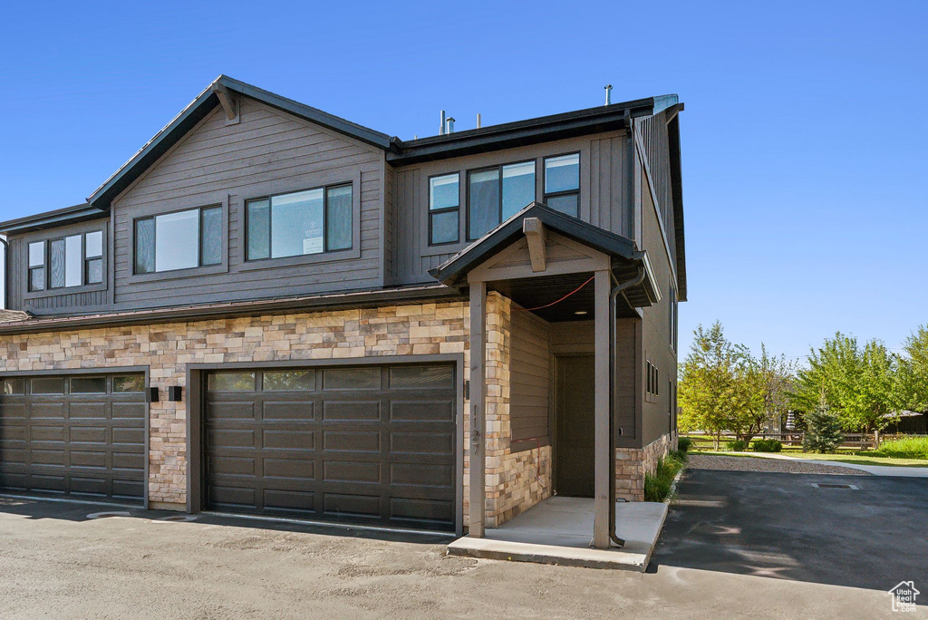 View of front of house with stone siding, an attached garage, and board and batten siding