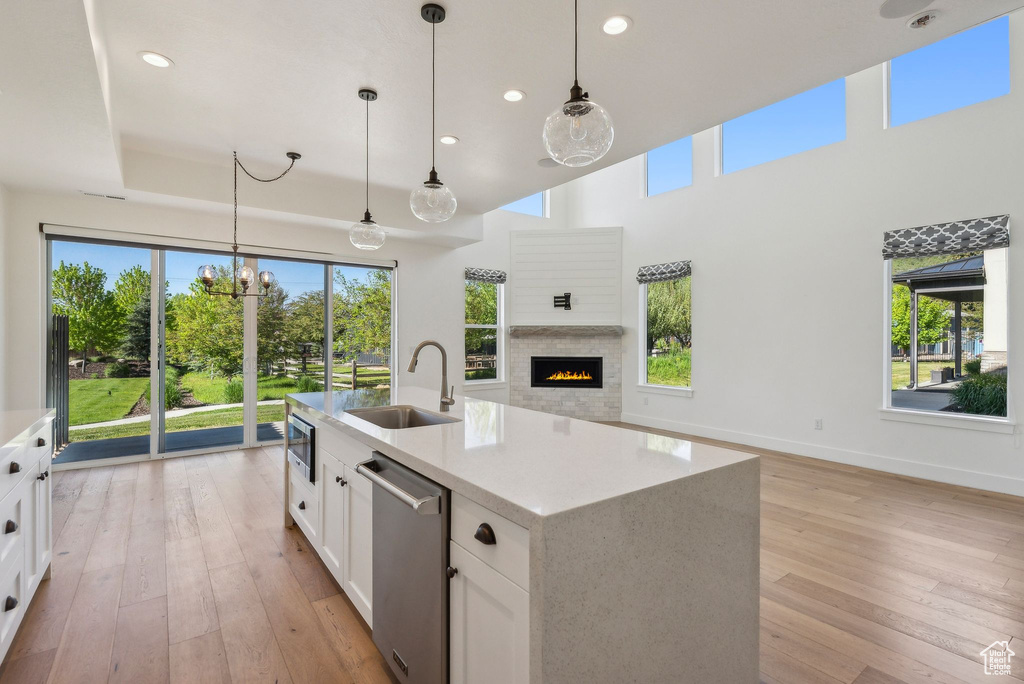 Kitchen featuring a sink, appliances with stainless steel finishes, open floor plan, light wood-style flooring, and white cabinetry