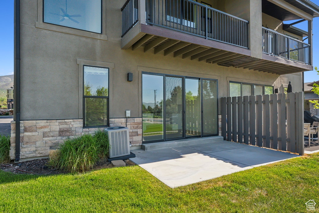 Back of property with a balcony, a patio area, and stucco siding