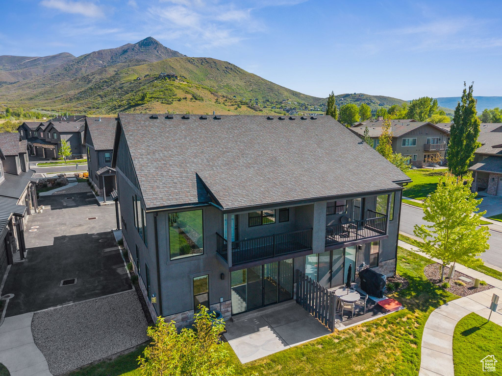Back of house with a balcony, a patio, a residential view, stucco siding, and a mountain view
