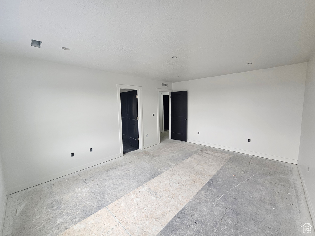 Unfurnished room with baseboards and a textured ceiling