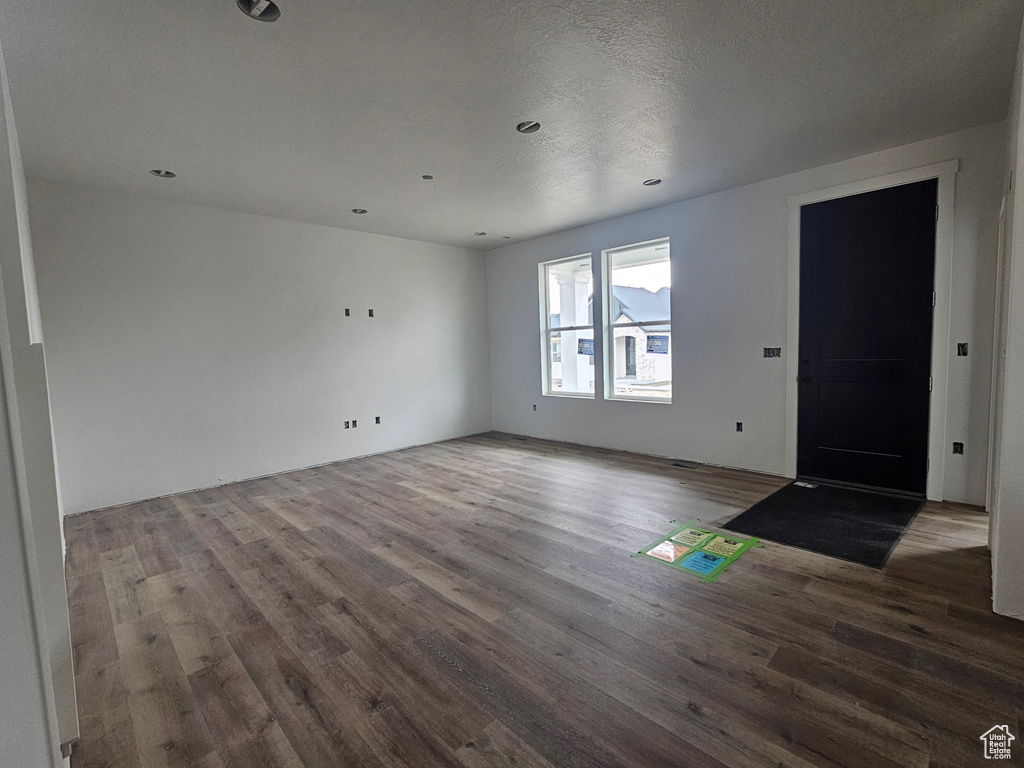 Unfurnished living room featuring a textured ceiling and wood finished floors
