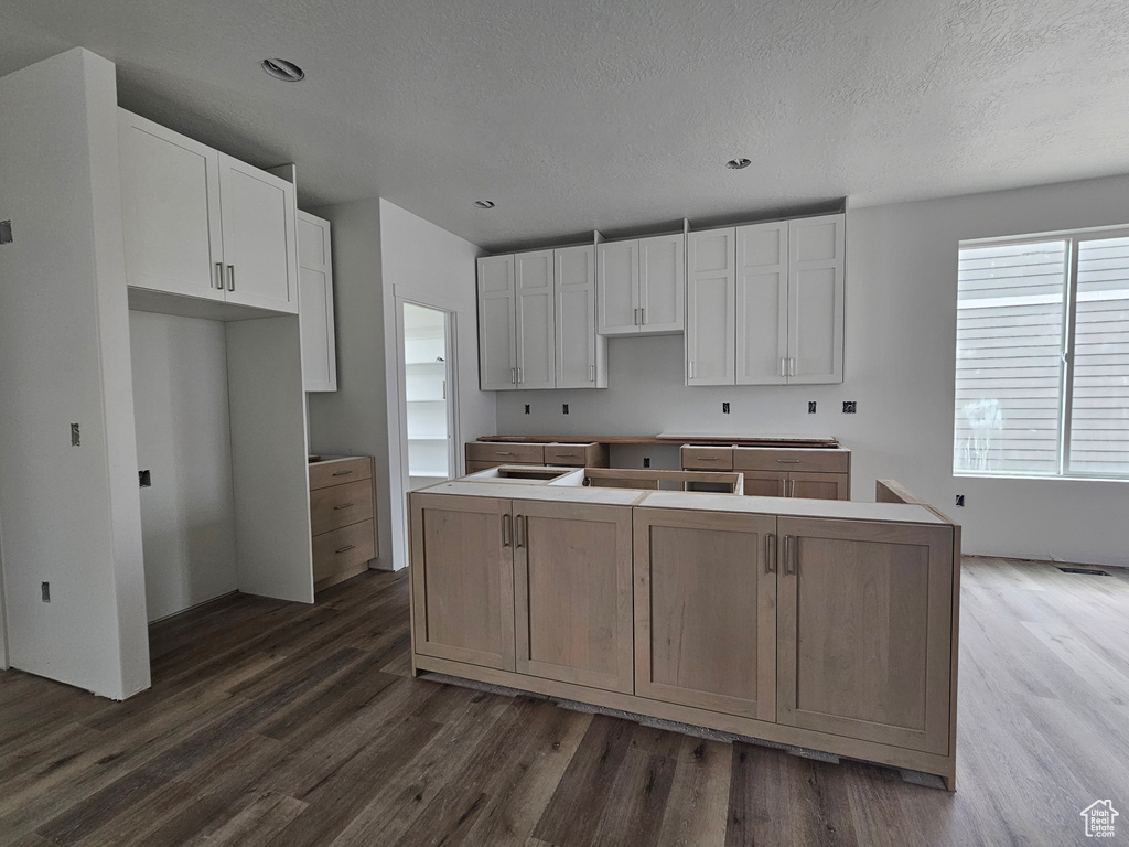 Kitchen with white cabinetry, dark wood-type flooring, a textured ceiling, and a kitchen island