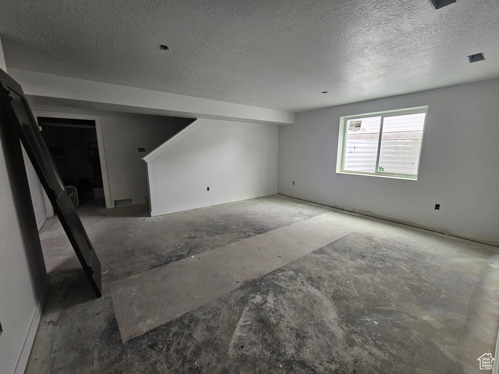 Below grade area featuring visible vents and a textured ceiling