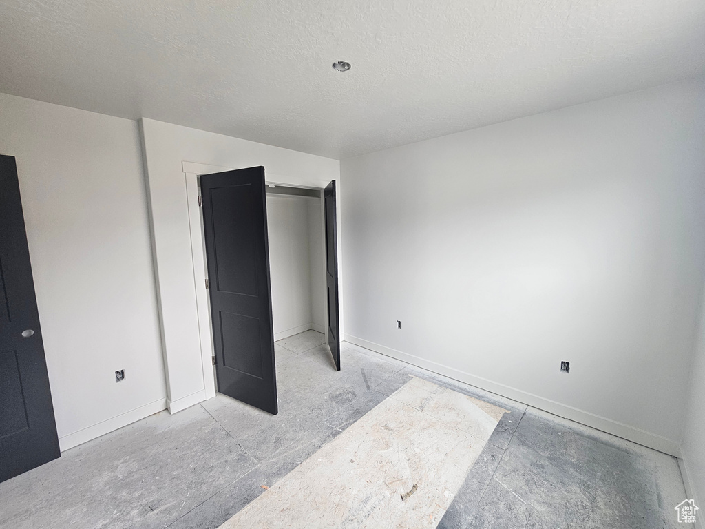 Unfurnished bedroom featuring a textured ceiling and baseboards