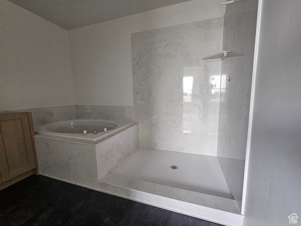 Bathroom featuring a garden tub, walk in shower, and wood finished floors