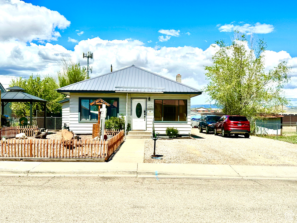 View of front facade featuring a gazebo, fence, a chimney, and metal roof