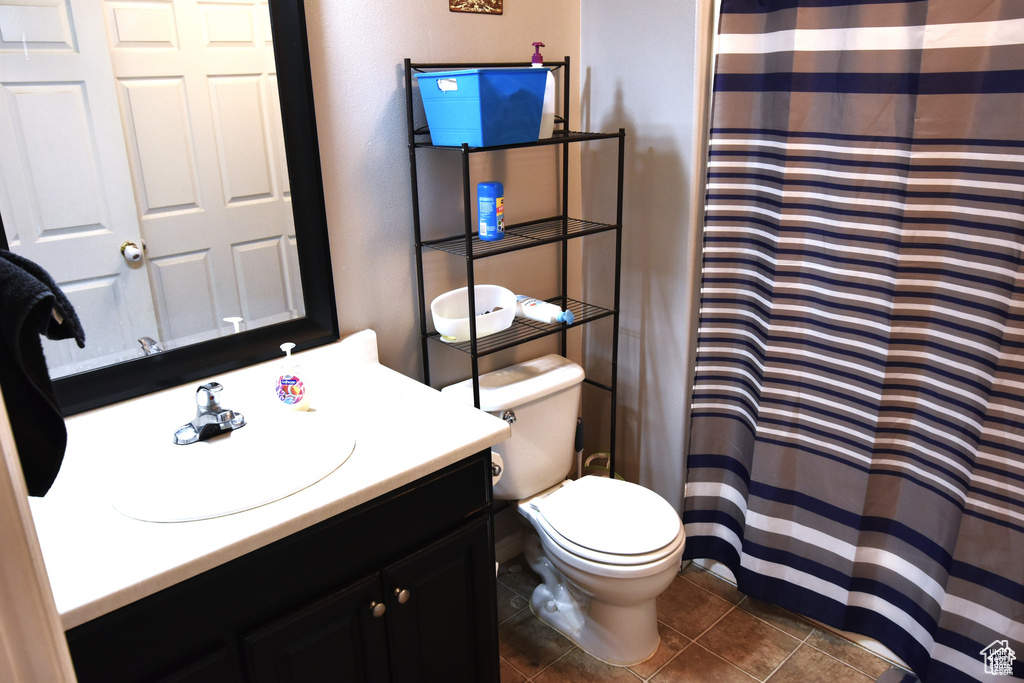 Full bath with tile patterned flooring, a shower with shower curtain, toilet, and vanity