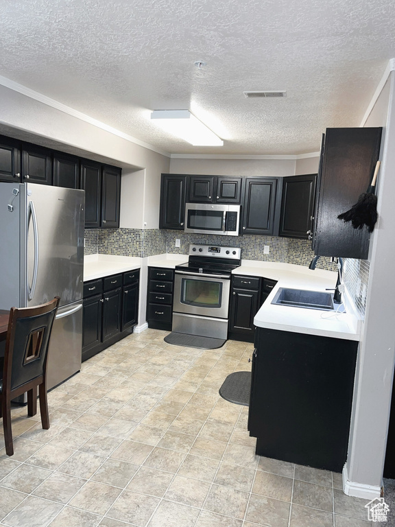 Kitchen with visible vents, a sink, dark cabinetry, appliances with stainless steel finishes, and light countertops