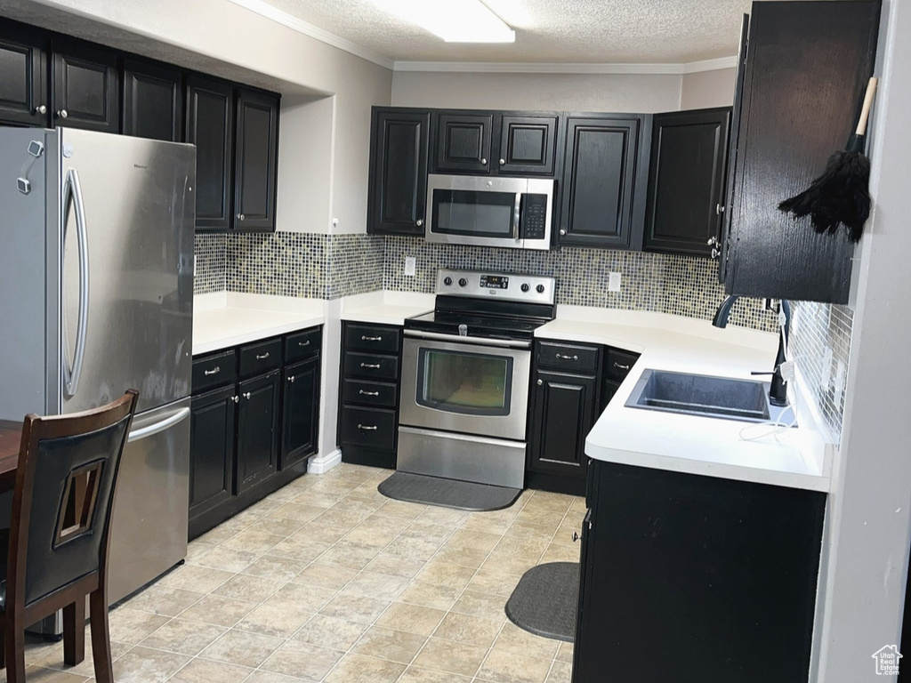 Kitchen with visible vents, a sink, dark cabinetry, appliances with stainless steel finishes, and light countertops