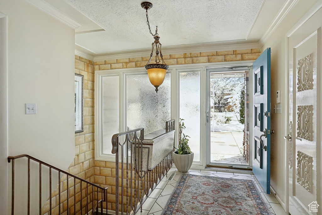 Entryway featuring crown molding, a textured ceiling, and light tile patterned flooring
