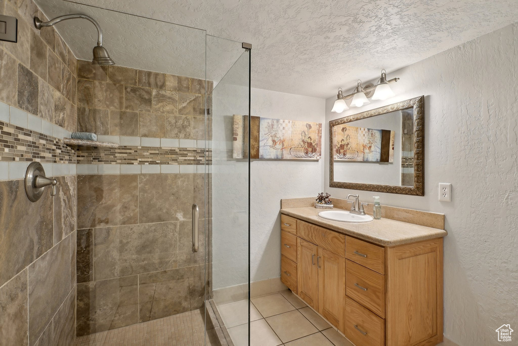 Bathroom with a textured ceiling, a stall shower, vanity, a textured wall, and tile patterned flooring