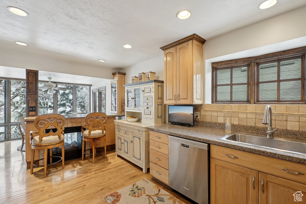 Kitchen with stainless steel dishwasher, a sink, plenty of natural light, light wood-style flooring, and recessed lighting