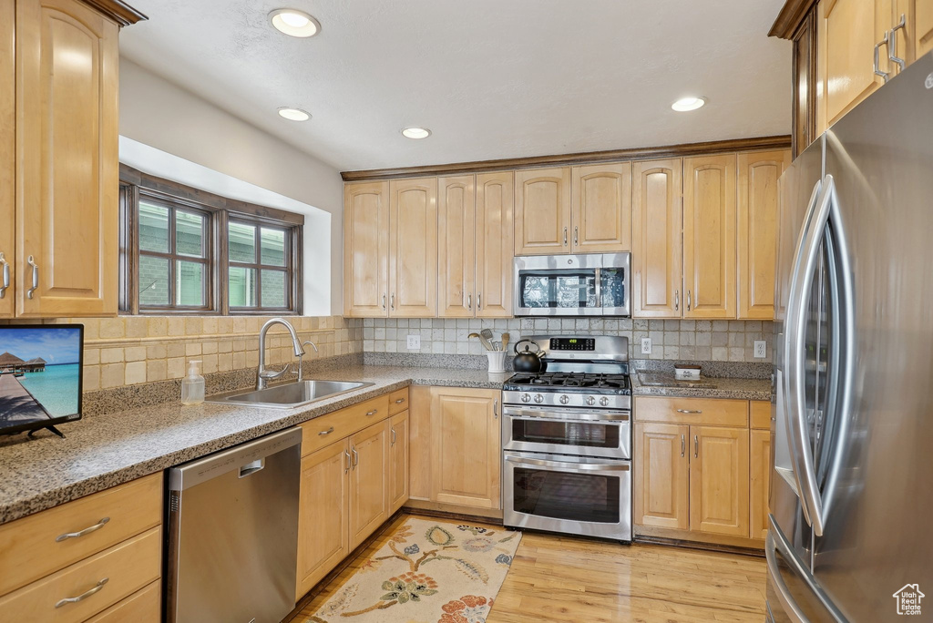 Kitchen with stainless steel appliances, a sink, light brown cabinetry, tasteful backsplash, and recessed lighting
