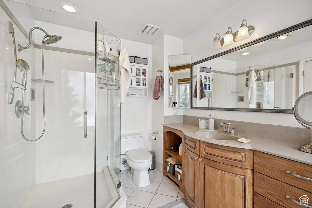 Full bathroom featuring toilet, a shower stall, tile patterned floors, and vanity