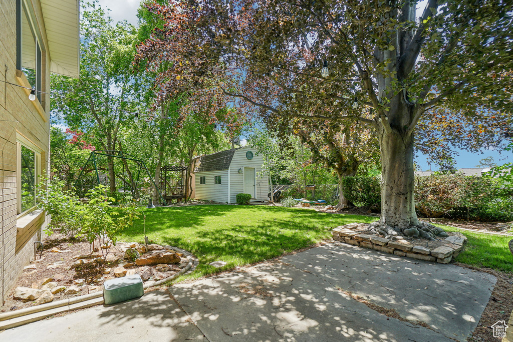View of grassy yard featuring a patio area and an outdoor structure