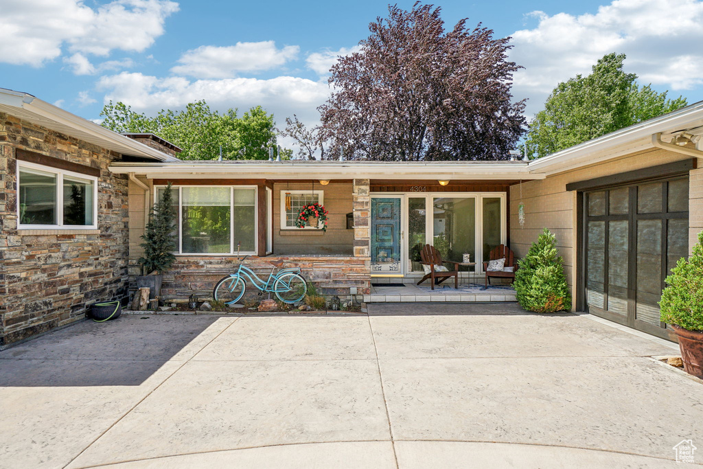 Property entrance featuring stone siding and a patio area
