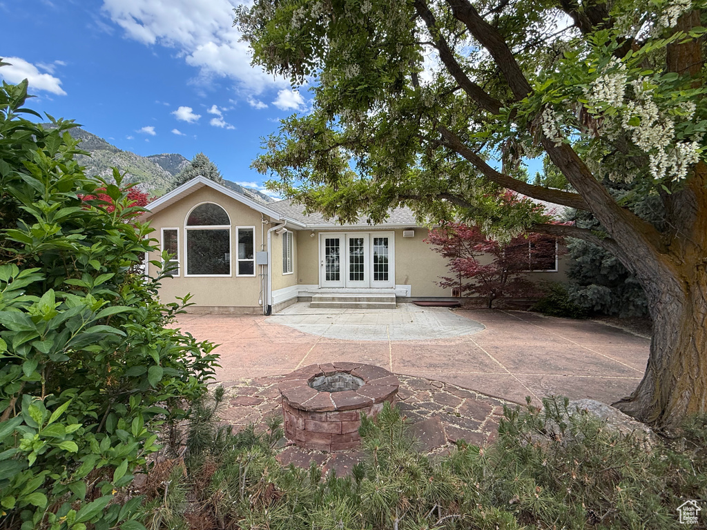 Rear view of property featuring french doors, stucco siding, a patio, and a fire pit